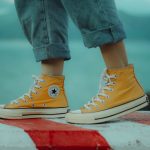 person wears yellow orange Converse All-Star high-top sneakers